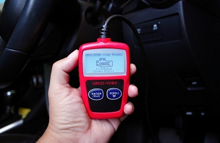 Vehicle owner holding a red OBDII scanner.