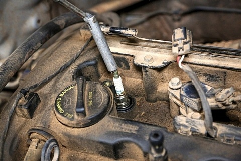 A spark plug and wire on a dusty old engine.