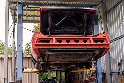 A red project car on a lift, under a carport.
